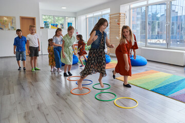 Small nursery school children with female teacher on floor indoors in classroom, doing exercise....