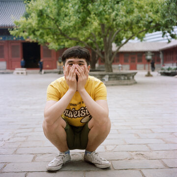 The man crouched with his hand covering his face