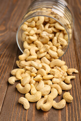 Jar with tasty cashew nuts on wooden background
