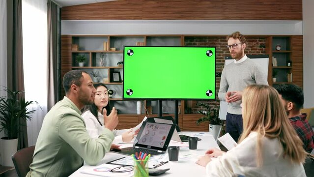Marketing strategy analysis, stock market trading or corporate teamwork. A team of startups at a table with a large green screen TV. Mixed race business team.