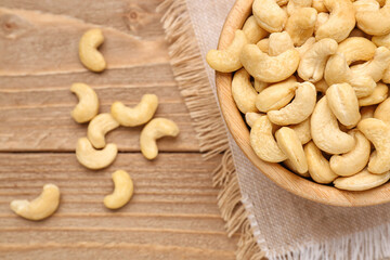 Bowl with tasty cashew nuts on wooden background