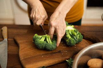 Person preparing broccoli by cutting them for cooking