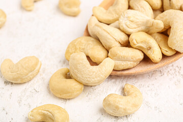 Fototapeta na wymiar Spoon with tasty cashew nuts on light background