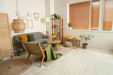 Interior of light living room with grey sofa, wooden armchair and coffee table