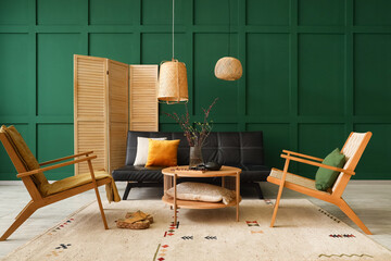 Interior of living room with black sofa, wooden armchairs and blooming tree branches on table