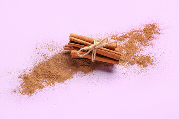 Bunch of cinnamon sticks and powder on color background