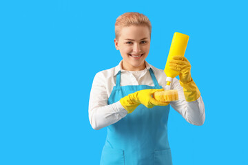 Young woman with cleaning sponge and detergent on blue background