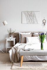 Interior of bright bedroom with beautiful iris flowers on bedside bench