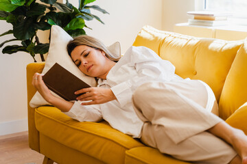 Relaxed Woman Reading Book On Sofa