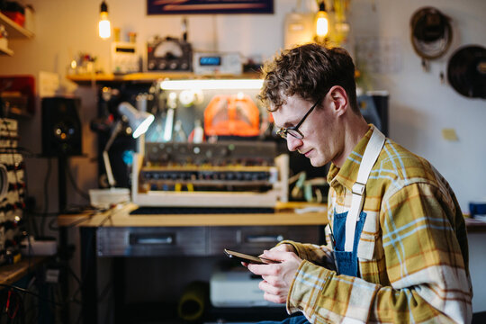 Master using smartphone in guitar amplifier repair shop