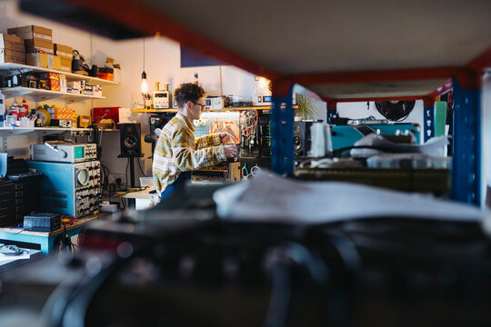 Focused master working in guitar amplifier repair shop