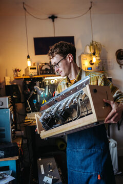 Enterprising guy carrying guitar amp in workshop