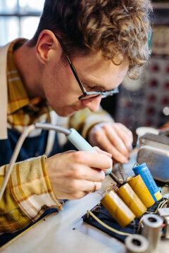 Repairman fixing capacitors of amplifier