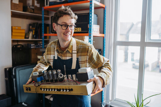 Smiling male master carrying details of guitar amp