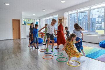 Small nursery school children with female teacher on floor indoors in classroom, doing exercise....