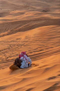 A Man With A Red Head Cover Sand Boarding In The Red Sand Desert In Dubai