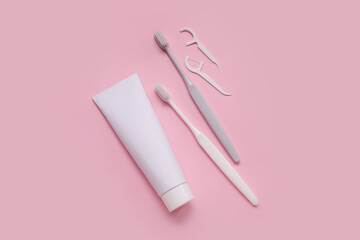 Plastic toothbrushes, toothpicks and paste on pink background