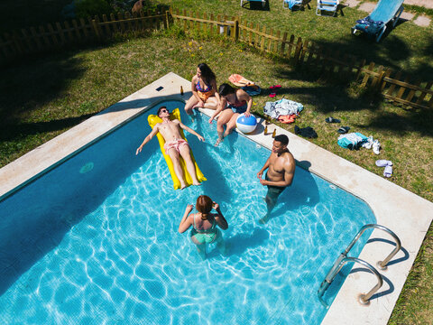 Drone view of a group of friends playing and having fun in the pool