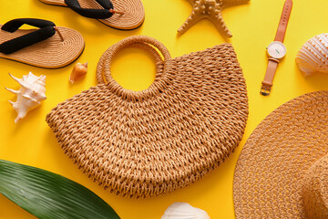 Composition with raffia bag, flip flops and shells on yellow background. Summer concept