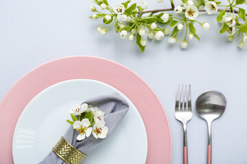 Beautiful table setting with blooming tree branches on grey background