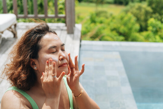 woman applying sunscreen in her face in a sunny day