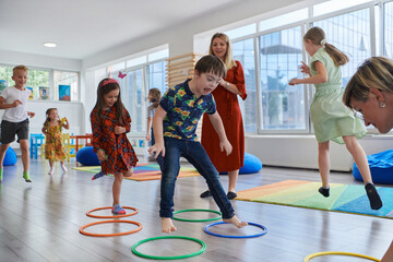 Small nursery school children with female teacher on floor indoors in classroom, doing exercise....