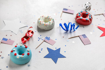 Composition with donuts, USA flags and confetti on white table. Independence Day celebration