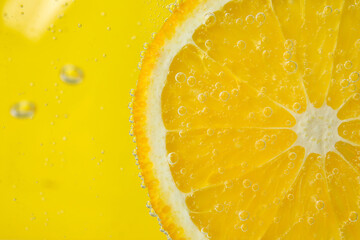 Lemon slice in water with bubbles on yellow background