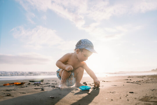 Toddler plays on beach at sunset.