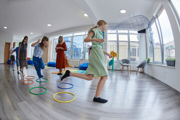 Small nursery school children with female teacher on floor indoors in classroom, doing exercise....