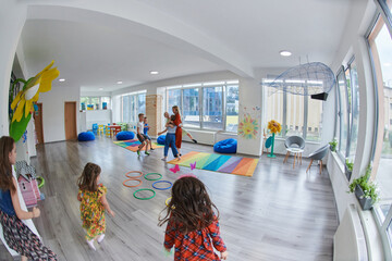 Small nursery school children with female teacher on floor indoors in classroom, doing exercise....