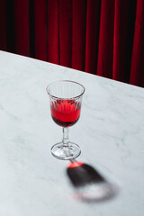 Lambrusco glass on a marble table with a red curtained background
