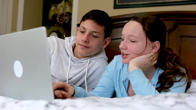 a boy and a girl on the bed near the computer having fun fooling around take their hands away from the keyboard pinch their fingers fight fight laugh have fun tickler spend time together look