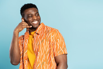 Portrait of handsome nigerian man showing hand gesture call on phone isolated on blue background