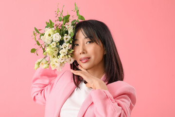 Beautiful Asian woman holding bouquet of eustoma flowers on pink background