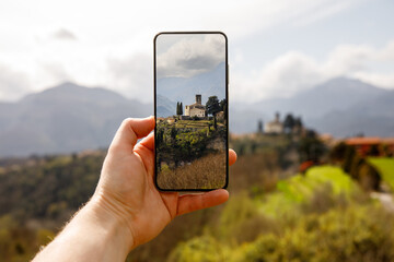 Travel photography: The tourist takes a photo of the beautiful Italian landscape using a mobile...