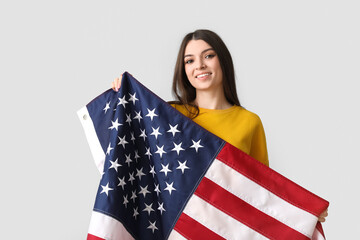 Young woman with USA flag on light background
