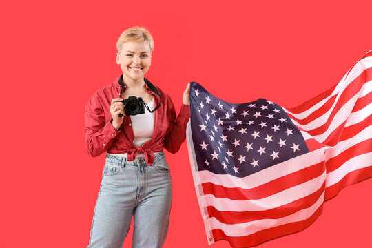 Young woman with photo camera and USA flag on red background