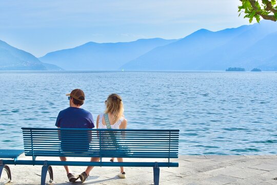 man and woman sitting on a bench by the lake