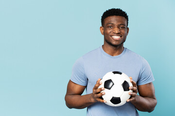 Smiling african american man holding soccer ball isolated on blue background copy space, advertising