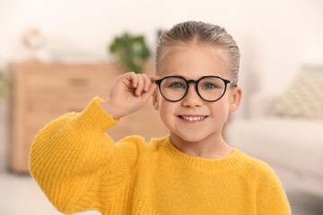 Portrait of cute little girl wearing glasses indoors