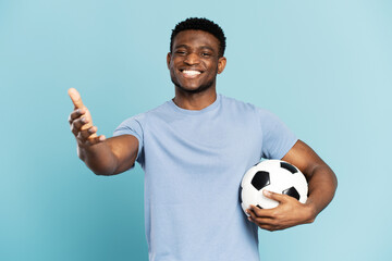 Professional African soccer player holding ball isolated on blue background