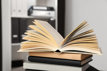 Stack of different hardcover books on wooden table indoors