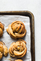 top view of Swedish cinnamon buns on a parchment lined baking sheet, cinnamon twists on a baking tray, top view of homemade Kanelbullar