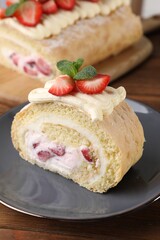 Delicious cake roll with strawberries and cream on gray plate