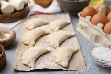 Raw dumplings (varenyky) with tasty filling on grey table, closeup. Traditional Ukrainian dish