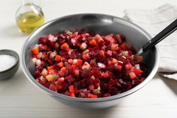 Bowl of delicious fresh vinaigrette salad on white wooden table, closeup