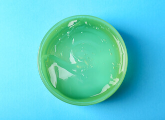 Aloe gel in jar on light blue background, top view
