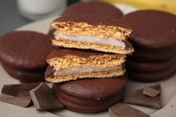 Tasty choco pies and pieces of chocolate on plate, closeup