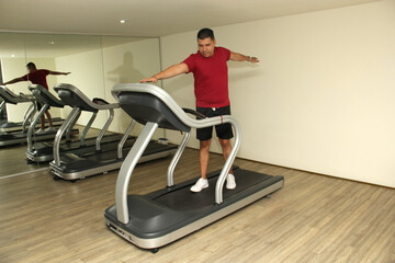 Fototapeta premium Forty-year-old dark-haired Latino adult man exercises his legs on the treadmill as a treatment for diseases such as tendonitis, tendon rupture or cruciate ligament injury